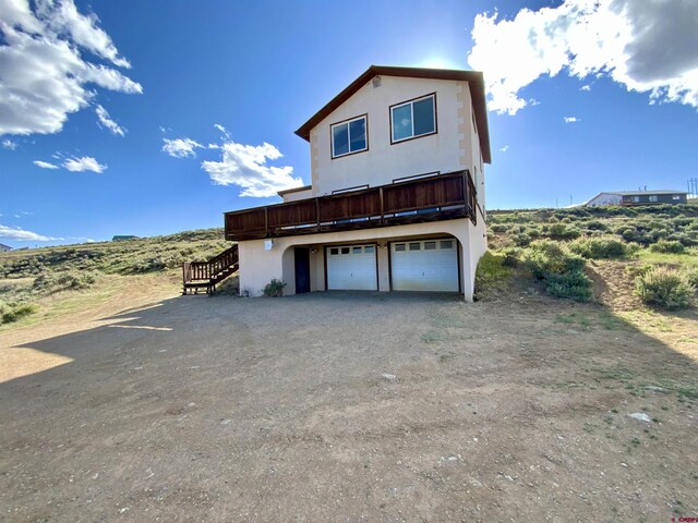 865 County Road 17, Gunnison, CO 81230 - view of property exterior with stucco siding, an attached garage, stairs, a deck, and dirt driveway