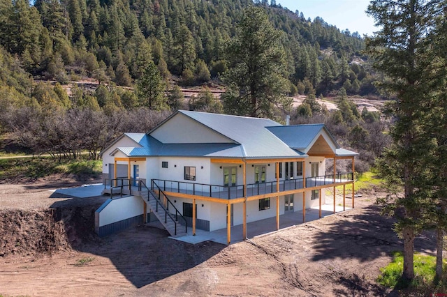 26217 Rd 38.5, Dolores, CO 81323 - back of property featuring a view of trees, metal roof, dirt driveway, a deck, and a patio