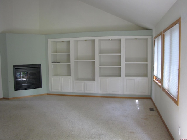 1770 Stellar Pl, Montrose, CO 81401 - unfurnished living room with lofted ceiling, a multi sided fireplace, built in shelves, baseboards, and light colored carpet