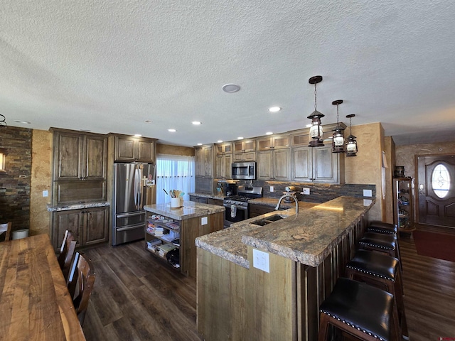 4189 Crowther Ln, Alamosa, CO 81101 - kitchen with appliances with stainless steel finishes, dark wood-style flooring, a sink, a textured ceiling, and stone counters