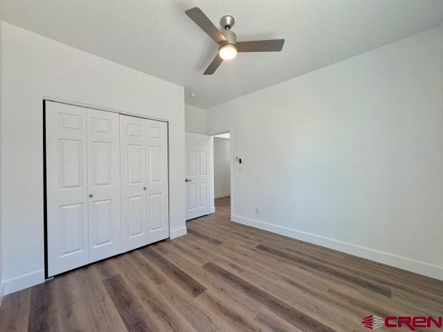 1911 Edison Ave, Alamosa, CO 81101 - unfurnished bedroom featuring baseboards, wood finished floors, a closet, and a ceiling fan