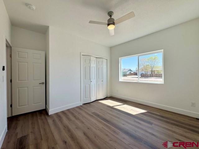 1911 Edison Ave, Alamosa, CO 81101 - unfurnished bedroom with baseboards, wood finished floors, a closet, and a ceiling fan