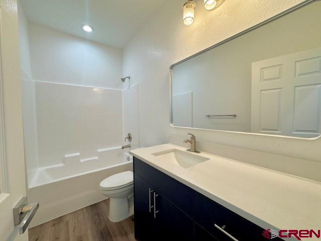1911 Edison Ave, Alamosa, CO 81101 - bathroom with vanity, toilet, wood finished floors, and shower / bath combination