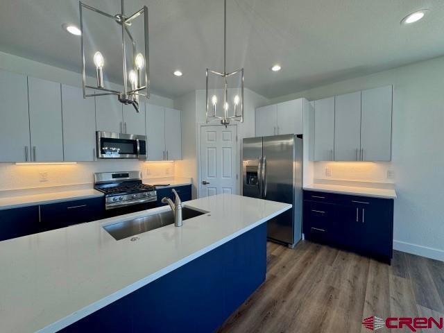 1911 Edison Ave, Alamosa, CO 81101 - kitchen with appliances with stainless steel finishes, a sink, a chandelier, wood finished floors, and light countertops