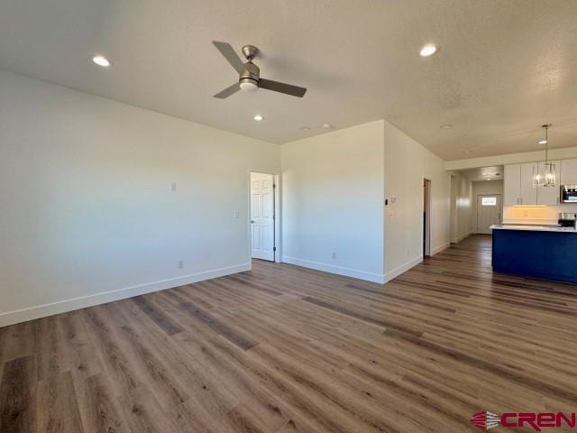 1911 Edison Ave, Alamosa, CO 81101 - unfurnished living room with ceiling fan, dark wood-style flooring, baseboards, recessed lighting, and a chandelier