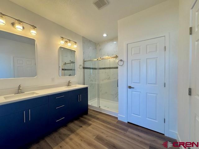 1911 Edison Ave, Alamosa, CO 81101 - bathroom with a marble finish shower, double vanity, wood finished floors, and recessed lighting