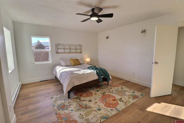 21603 Vaca Dr, Eckert, CO 81418 - bedroom with a baseboard radiator, wood finished floors, baseboards, and a ceiling fan