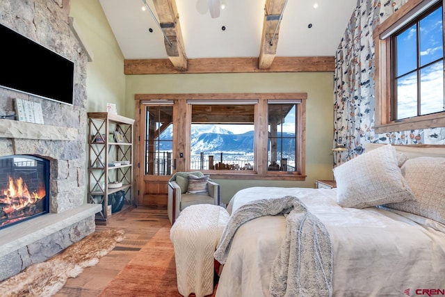 426 Saddle Ridge Ranch Rd, Crested Butte, CO 81224 - bedroom with wood finished floors, a mountain view, a stone fireplace, and multiple windows