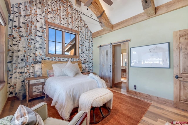 426 Saddle Ridge Ranch Rd, Crested Butte, CO 81224 - bedroom featuring a barn door, wood finished floors, beam ceiling, baseboards, and connected bathroom