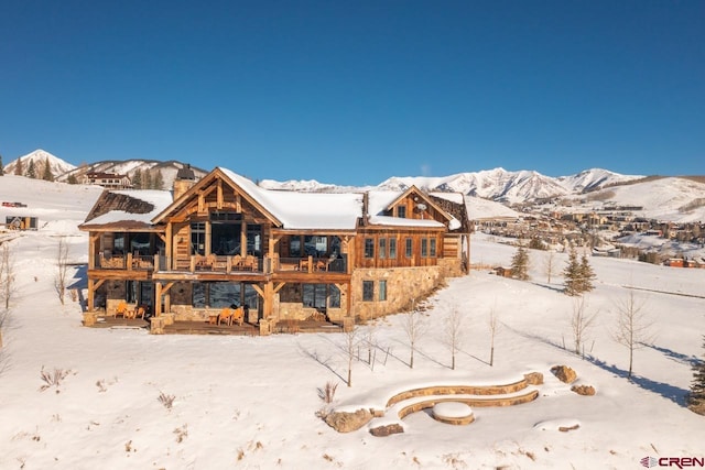 426 Saddle Ridge Ranch Rd, Crested Butte, CO 81224 - snow covered rear of property featuring stone siding, a balcony, a mountain view, and a chimney
