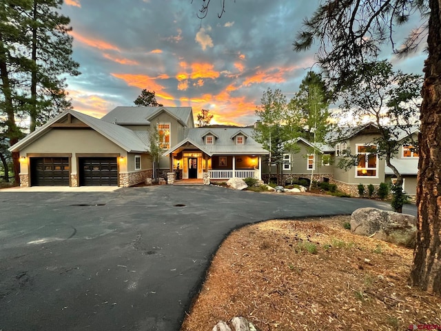 575 County Rd 253, Durango, CO 81301 - view of front of property with stone siding, a porch, driveway, an attached garage, and stucco siding