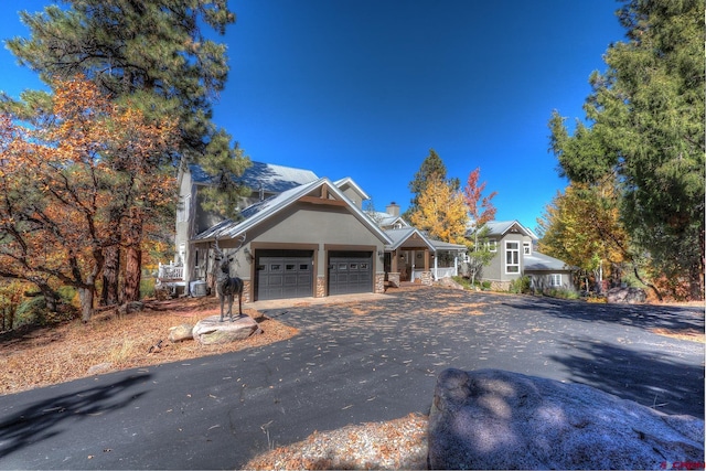 575 County Rd 253, Durango, CO 81301 - view of front of house with asphalt driveway, a garage, a chimney, stone siding, and stucco siding