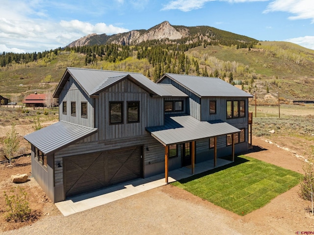 64 Buckhorn Way, Crested Butte, CO 81224 - modern farmhouse style home with metal roof, asphalt driveway, a porch, a mountain view, and a garage