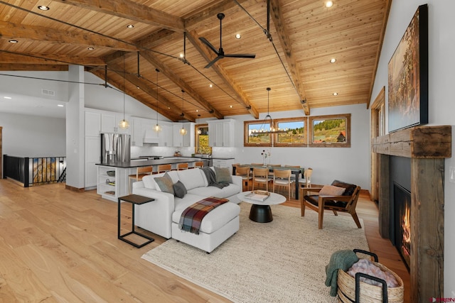 64 Buckhorn Way, Crested Butte, CO 81224 - living room with wood ceiling with exposed beams, light wood-style floors, a lit fireplace, ceiling fan, and high vaulted ceiling