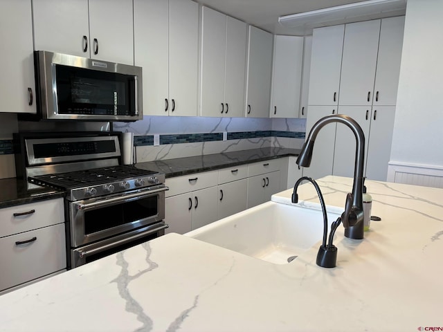 541 Perry Dr, Pagosa Springs, CO 81147 - kitchen with stainless steel appliances, dark stone counters, white cabinetry, and a sink