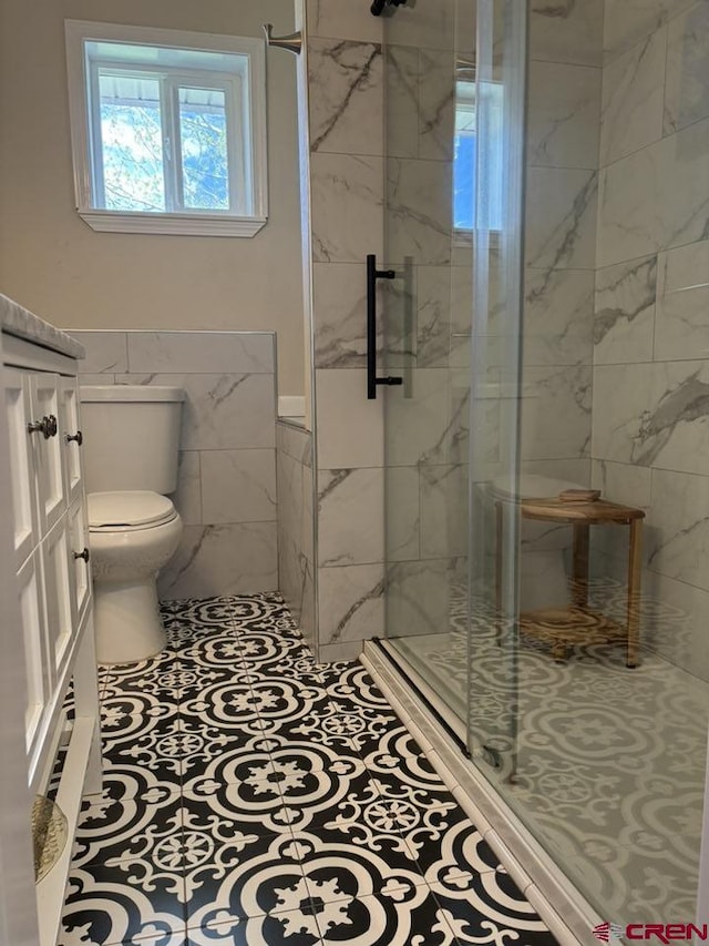 541 Perry Dr, Pagosa Springs, CO 81147 - bathroom featuring tile walls, a stall shower, toilet, and wainscoting