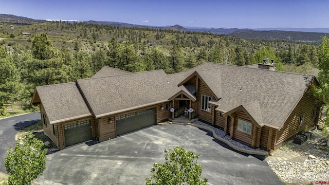 50 W Durango Ridge Rd, Durango, CO 81301 - view of front facade with a wooded view, a garage, driveway, a shingled roof, and a chimney