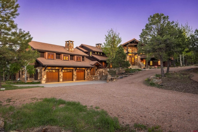 182 Juniper Rd S, Ridgway, CO 81432 - view of front facade featuring curved driveway, stone siding, an attached garage, a chimney, and a tile roof