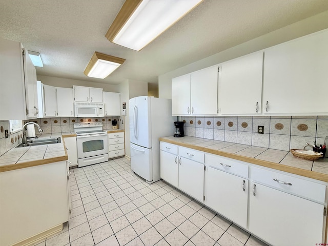 2020 Essex St, Montrose, CO 81401 - kitchen with white appliances, a sink, decorative backsplash, and white cabinetry