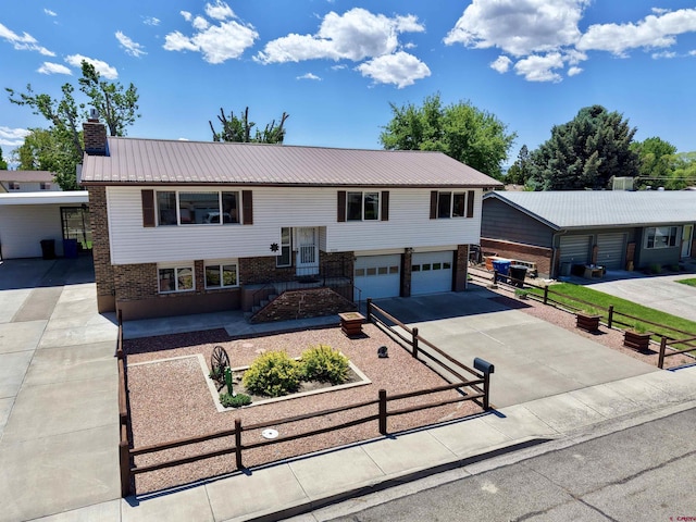 2020 Essex St, Montrose, CO 81401 - split foyer home with asphalt driveway, brick siding, metal roof, a chimney, and an attached garage