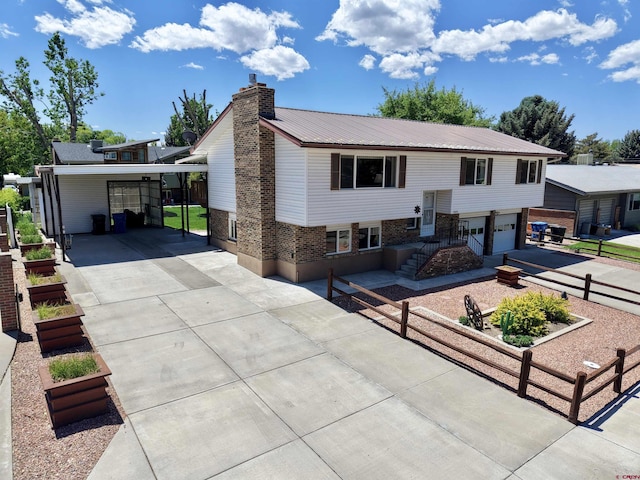 2020 Essex St, Montrose, CO 81401 - raised ranch featuring concrete driveway, a vegetable garden, a chimney, brick siding, and a garage