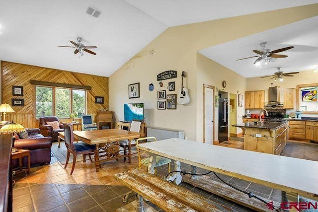 538 Rugby Mines Rd, Walsenburg, CO 81089 - dining area featuring a ceiling fan, wooden walls, lofted ceiling, and dark tile patterned floors