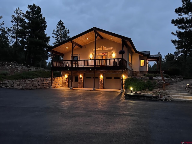 520B Whispering Wood Dr, Pagosa Springs, CO 81147 - view of front of home with stone siding, asphalt driveway, stucco siding, a garage, and a deck