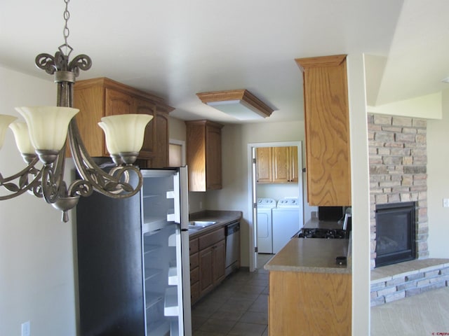 1756 Freedom Way, Montrose, CO 81401 - kitchen featuring washing machine and clothes dryer, stainless steel dishwasher, tile patterned flooring, a chandelier, and a fireplace