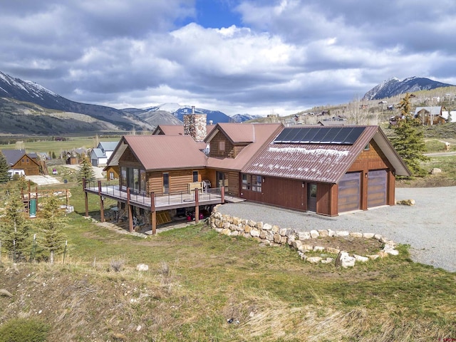 156 Zeligman St, Crested Butte, CO 81224 - view of front of house with roof mounted solar panels, a chimney, a garage, a deck with mountain view, and metal roof