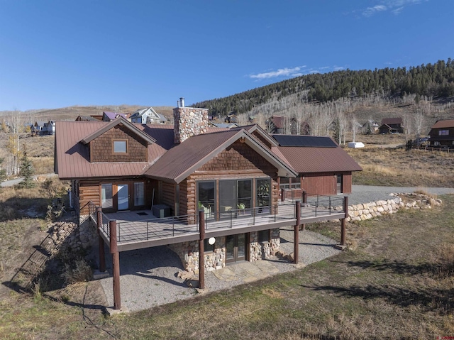 156 Zeligman St, Crested Butte, CO 81224 - back of property featuring a deck, metal roof, a chimney, and a patio area