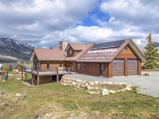 156 Zeligman St, Crested Butte, CO 81224 - view of front of property featuring a chimney, roof mounted solar panels, metal roof, a garage, and a front lawn