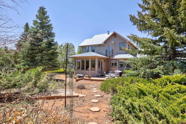 15307 Rd R, Cahone, CO 81320 - rear view of property featuring a sunroom, metal roof, and a patio area