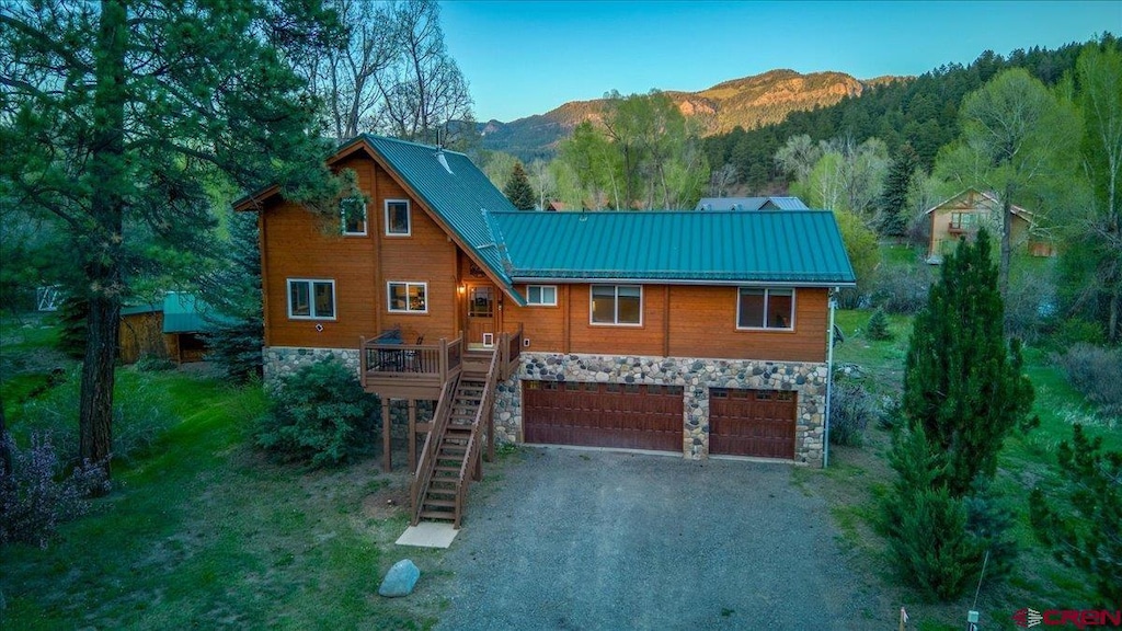 12 Bridge Dr, Pagosa Springs, CO 81147 - view of front facade featuring stone siding, a garage, a mountain view, and stairway