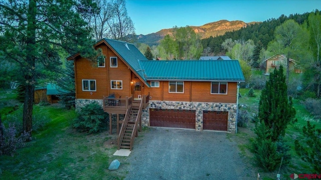 12 Bridge Dr, Pagosa Springs, CO 81147 - view of front facade featuring stone siding, a garage, a mountain view, and stairway