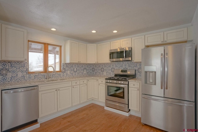 511 E Garland St, La Veta, CO 81055 - kitchen featuring stainless steel appliances, a sink, light wood-style floors, light stone counters, and tasteful backsplash