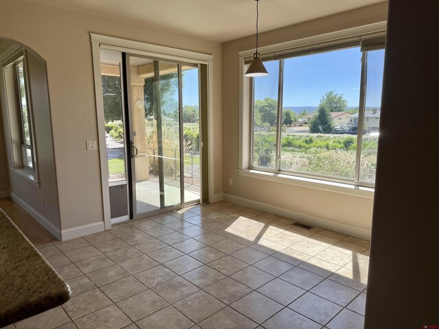 1252 Peppertree Dr, Montrose, CO 81401 - unfurnished dining area with baseboards, arched walkways, and tile patterned flooring