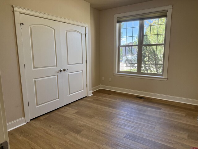 1252 Peppertree Dr, Montrose, CO 81401 - unfurnished bedroom with baseboards, wood finished floors, and multiple windows