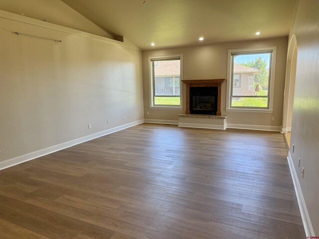 1252 Peppertree Dr, Montrose, CO 81401 - unfurnished living room with plenty of natural light, a glass covered fireplace, dark wood-style floors, vaulted ceiling, and recessed lighting