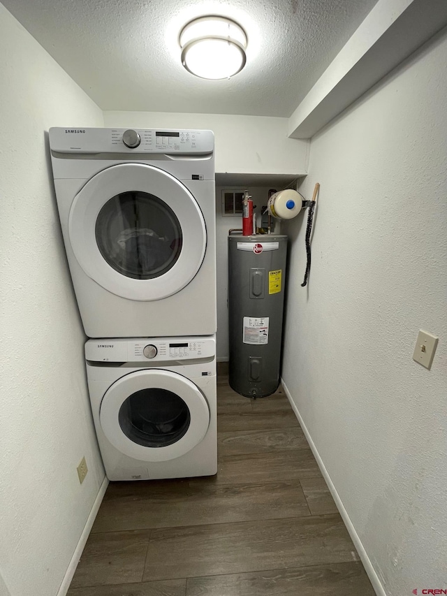 516 N 14th St Unit A, Gunnison, CO 81230 - laundry area with stacked washer / dryer, electric water heater, wood finished floors, a textured ceiling, and baseboards