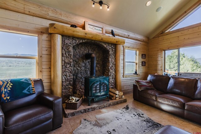 2439 County Road 359, Pagosa Springs, CO 81147 - tiled living area featuring plenty of natural light, a wood stove, vaulted ceiling, and wooden walls