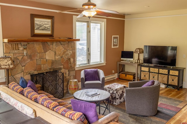 51 Blake St, Placerville, CO 81430 - living room with a baseboard radiator, wood finished floors, a ceiling fan, and a stone fireplace