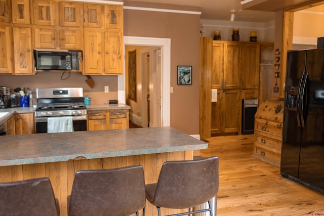 51 Blake St, Placerville, CO 81430 - kitchen with black appliances, a breakfast bar, light wood-style flooring, and a peninsula