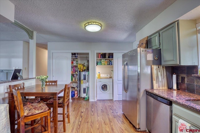 43 W Radiant Ct, Pagosa Springs, CO 81147 - kitchen featuring washer / dryer, appliances with stainless steel finishes, light wood-style floors, a textured ceiling, and dark countertops