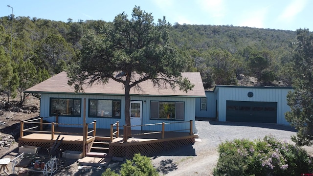 17992 Hanson Rd, Cedaredge, CO 81413 - view of front of house with a view of trees, a wooden deck, driveway, and roof with shingles