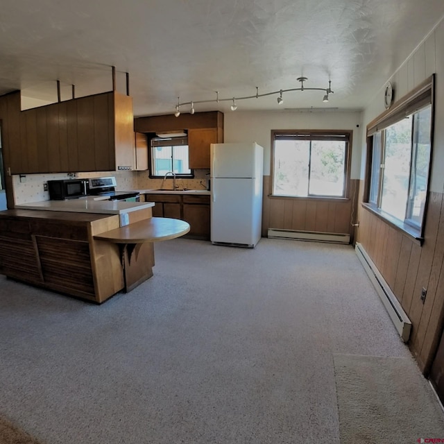 17992 Hanson Rd, Cedaredge, CO 81413 - kitchen with freestanding refrigerator, a baseboard radiator, stainless steel range with electric stovetop, a sink, and wood walls