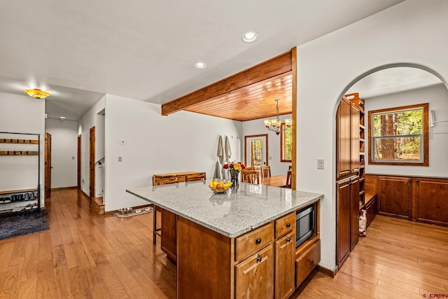 380 Eagle Pass, Durango, CO 81301 - kitchen featuring stainless steel microwave, light wood-type flooring, arched walkways, light stone counters, and a chandelier