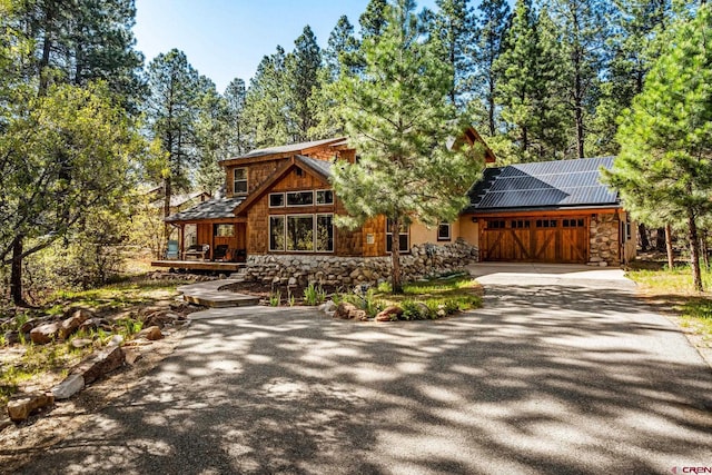380 Eagle Pass, Durango, CO 81301 - rustic home featuring stone siding, driveway, a garage, roof mounted solar panels, and a porch
