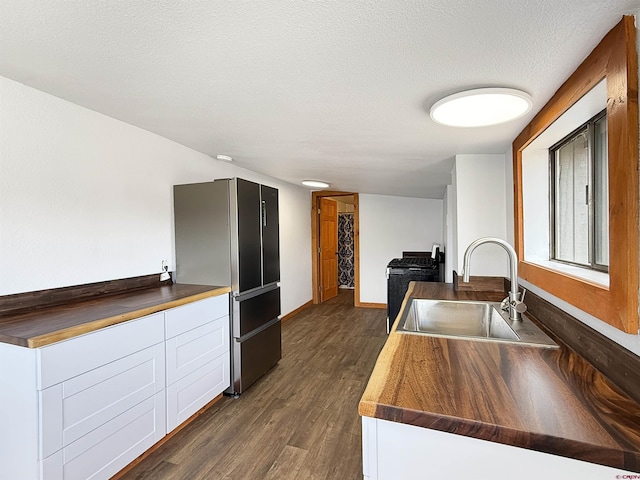 1246 Meeker St, Delta, CO 81416 - kitchen featuring freestanding refrigerator, a sink, dark wood-style flooring, baseboards, and white cabinets