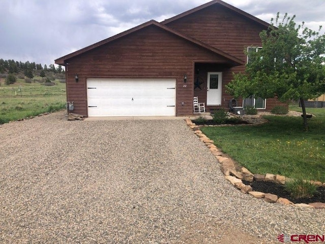 22 Lancer Ct, Pagosa Springs, CO 81147 - view of front of home featuring gravel driveway, a front yard, and an attached garage