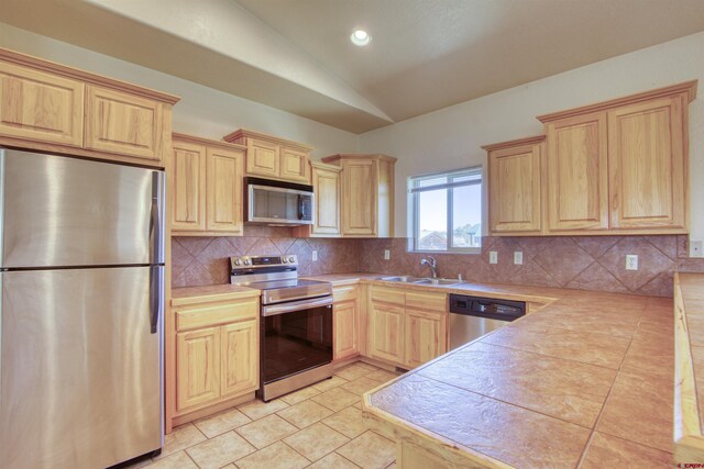2038 Park Ave, Pagosa Springs, CO 81147 - kitchen featuring appliances with stainless steel finishes, light brown cabinets, a sink, lofted ceiling, and tile countertops